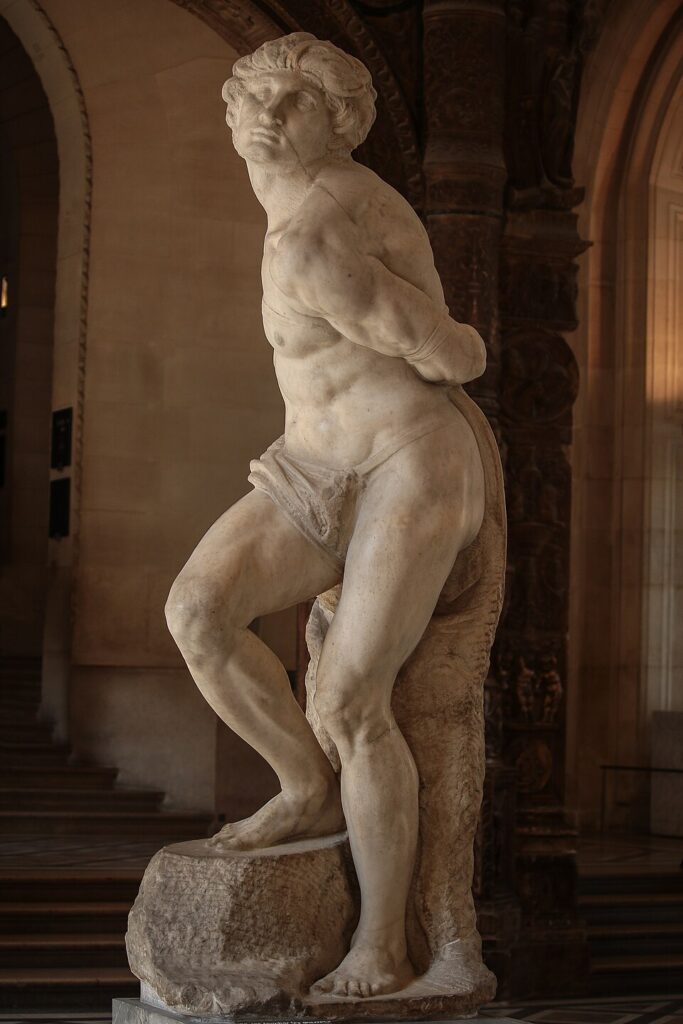 'Rebellious Slave', by Michelangelo - A marble statue depicting a muscular man bound with his hands behind his back