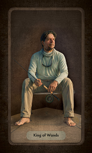 The King of Wands depicts an older man, a fly fisherman, sitting on the bow of a flats skiff staring into the distance