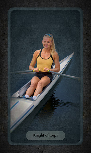 The Knight of Cups shows a young woman rowing a single scull on calm water. SHe wears a yellow jersey and black shorts. She is smiling warmly.