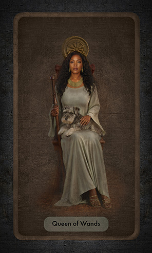 The Queen of Wands shows a Black woman with cascading wavy hair sitting on a small wooden throne with a burnished decoration behind her head. She holds a staff in her right hand and a miniature schnauzer rests on her lap.